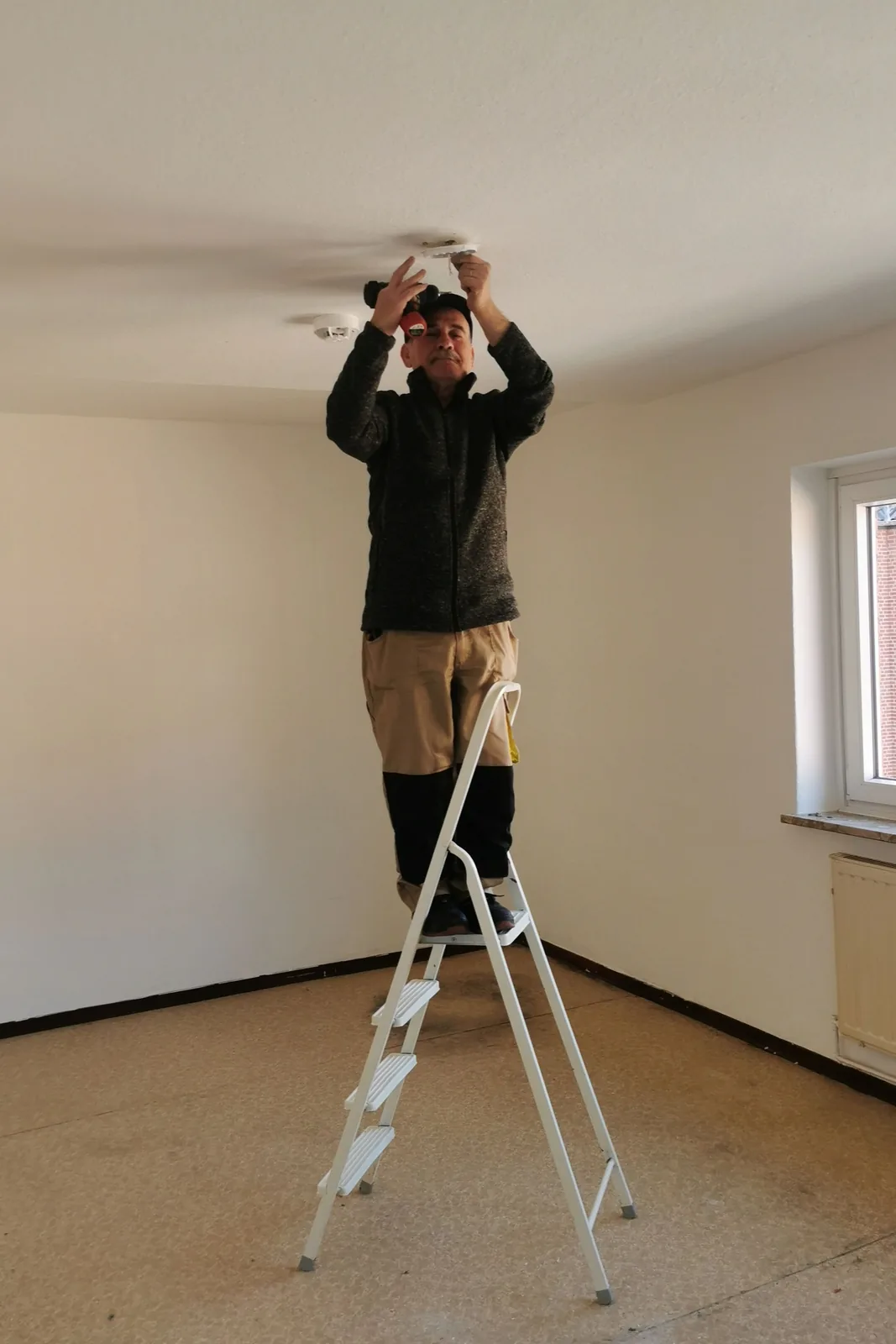 Fitting a ceiling detector from a step ladder, for ceiling fan installation in Detroit