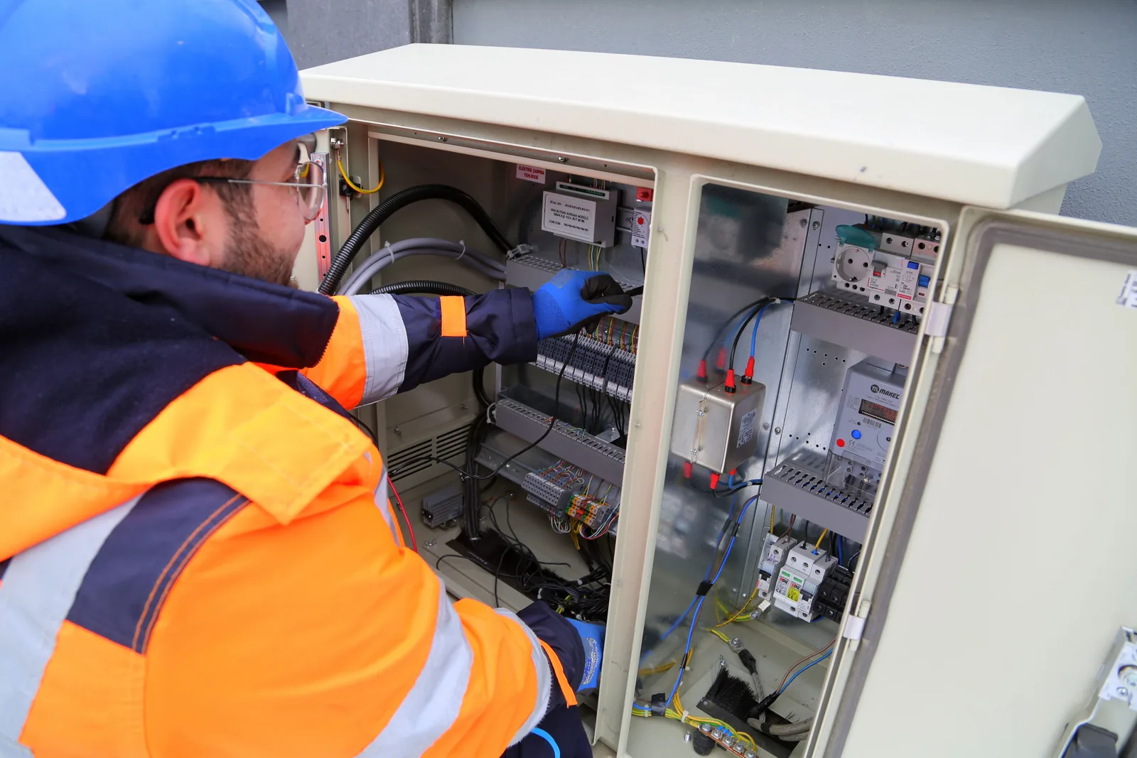 An electrician working in an outdoor service cabinet, for maintenance plans in Detroit